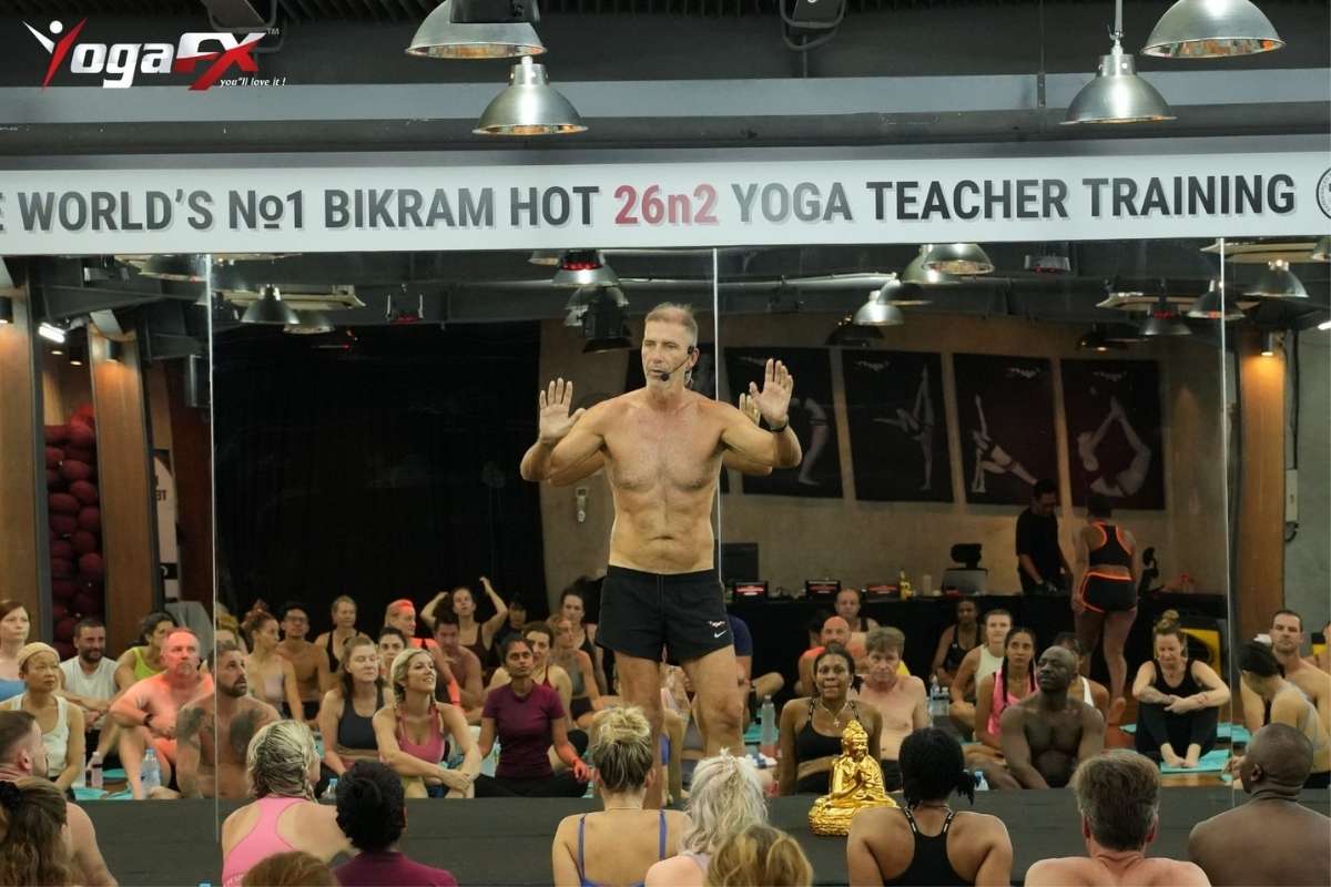 Yoga instructor correcting a student's posture alignment during a supervised teacher training class
