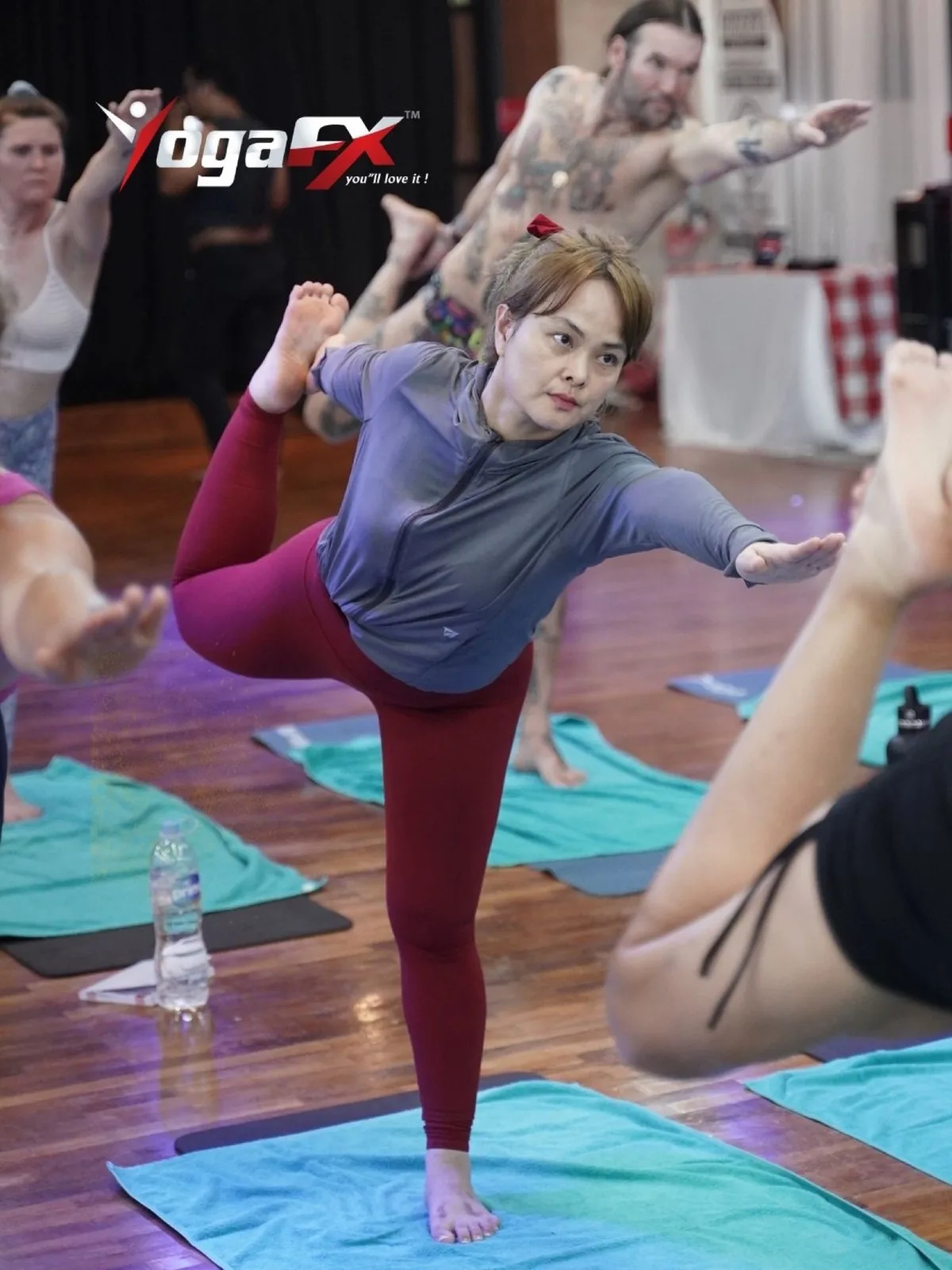 Student balancing on one leg in a hot yoga class, a held balance rather than a vinyasa transition