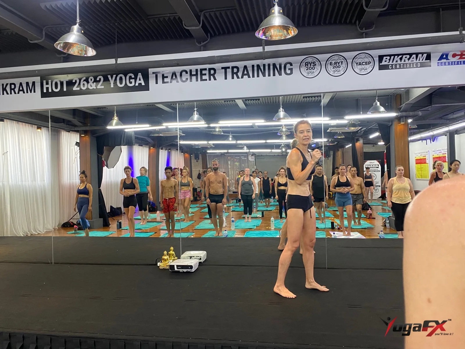 How many men do yoga: men and women standing side by side in a mixed hot yoga class as the teacher speaks