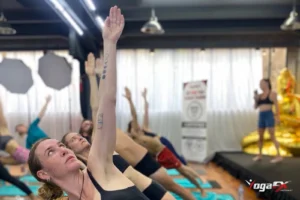 Yoga benefits for men and women alike: a full hot yoga class standing in a side-bend stretch on teal mats